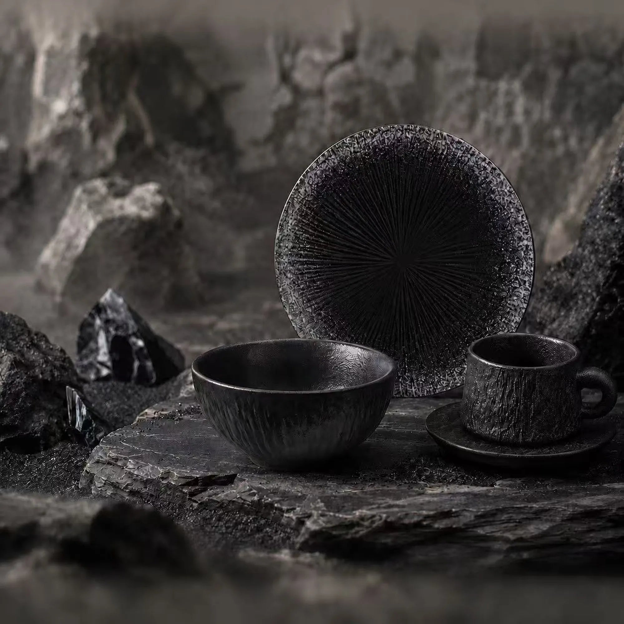 Obsidian ceramic dinnerware collection inspired by volcanic stone, featuring black ceramic plates, bowls and cups.