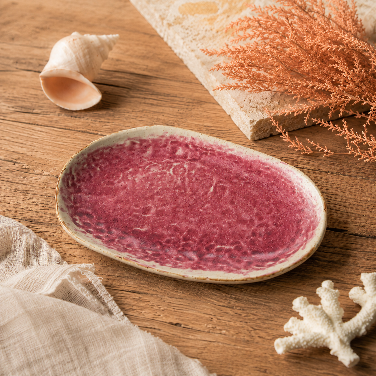 Coral pink ceramic oval plate styled on a warm dining table