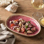 Coral pink ceramic oval plate styled with plated food