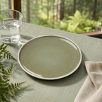Moss green ceramic dinnerware styled on a modern dining table