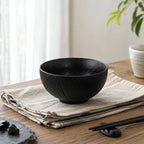 Obsidian black ceramic rice bowl styled on a minimalist dining table