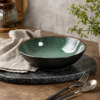 Peacock green ceramic pasta bowl styled on a modern dining table