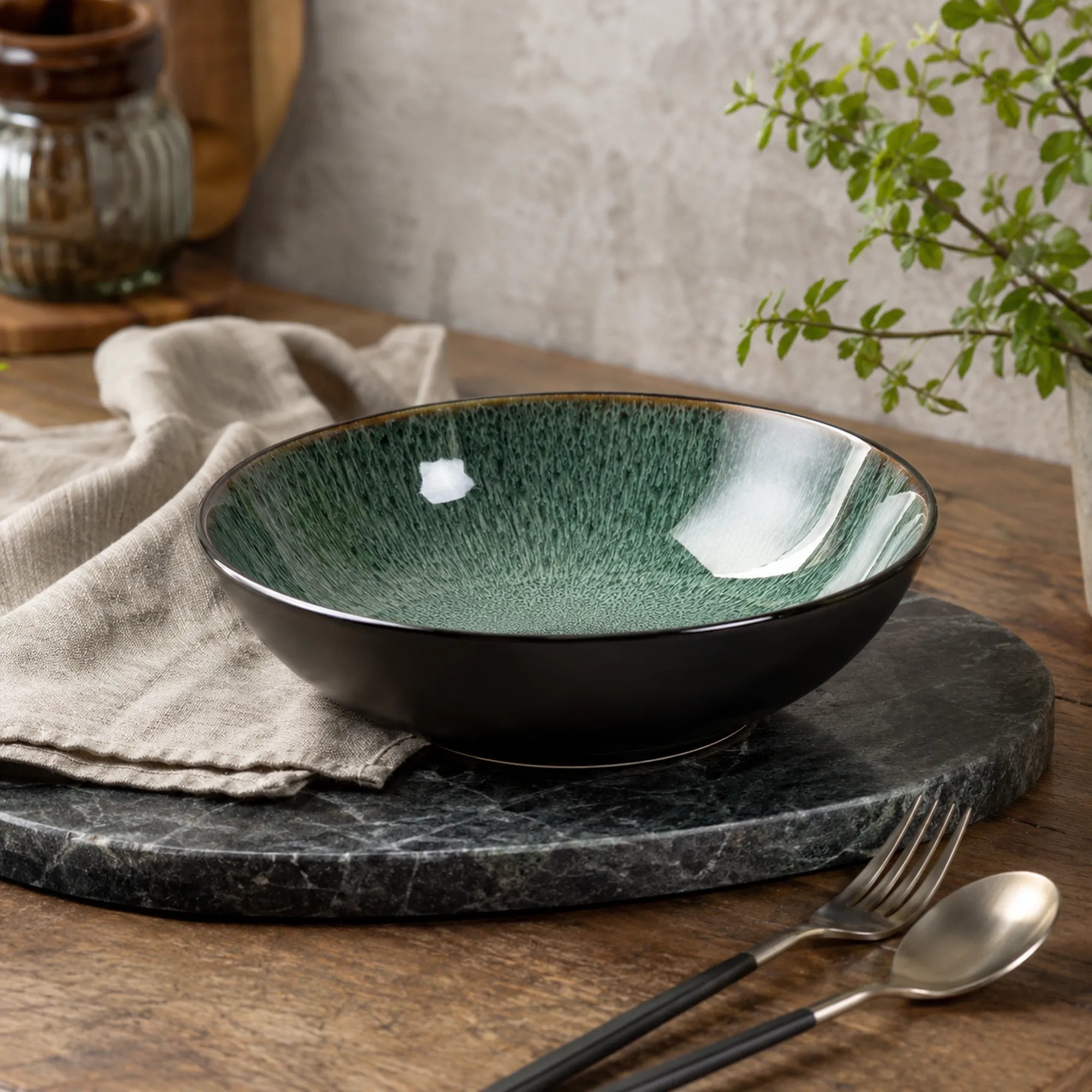 Peacock green ceramic pasta bowl styled on a modern dining table