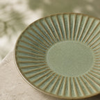 Sage green ceramic dinnerware styled on a calm dining table