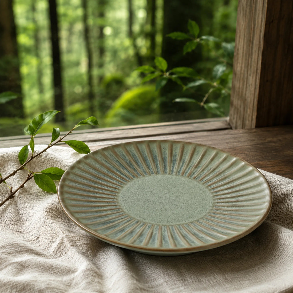 Sage green ceramic dinnerware styled on a calm dining table