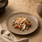 Sand brown ceramic dinner plate styled with warm food