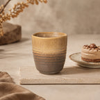Sand brown ceramic tea cup styled in a warm tea setting