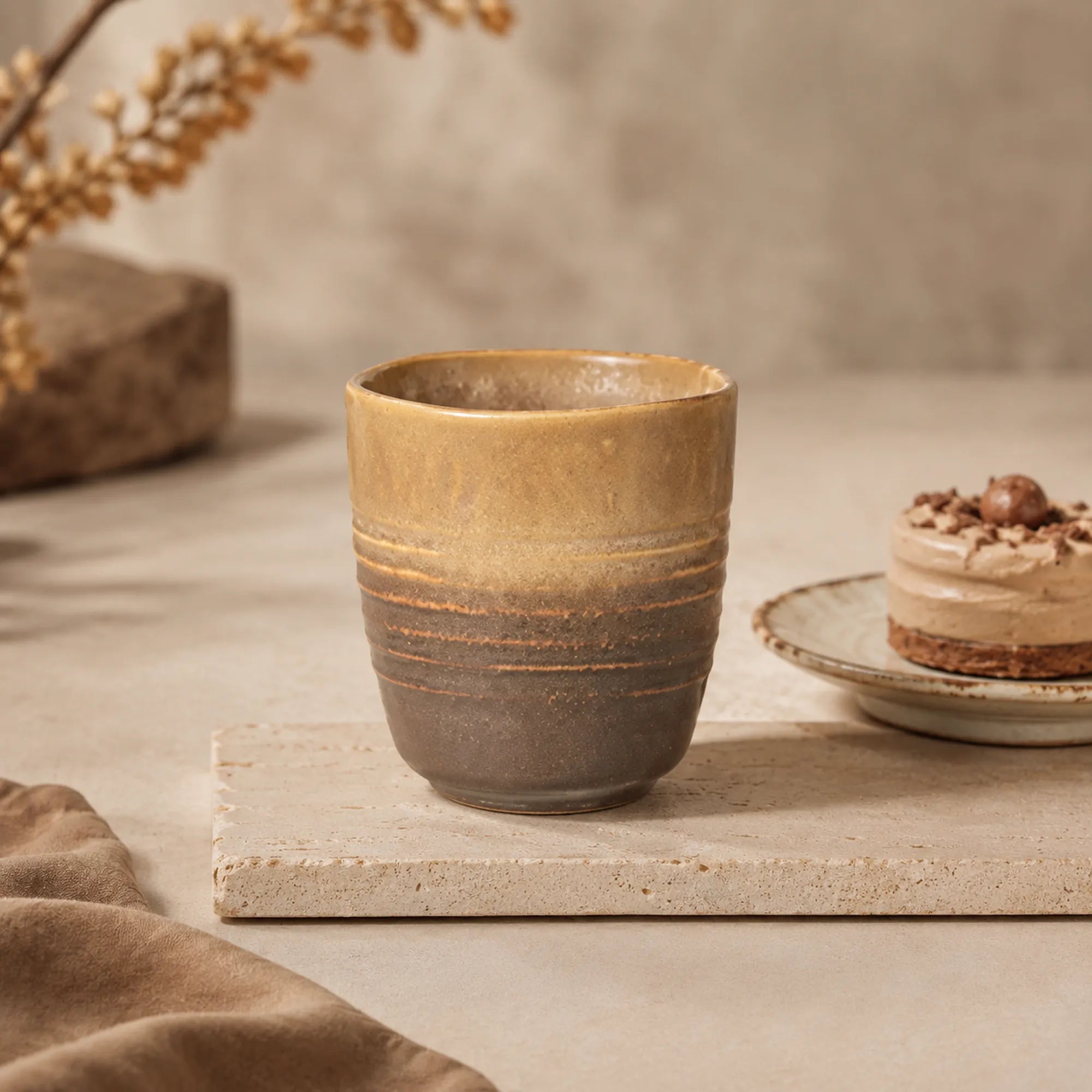 Sand brown ceramic tea cup styled in a warm tea setting